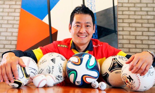 사인이 담긴 축구공과 야구공을 앞에 둔 인물